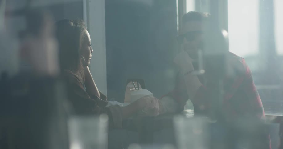 A man and woman hold hands as they sit outside