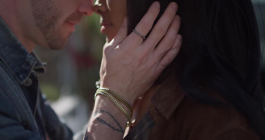 Man and woman kiss as the man caresses her face