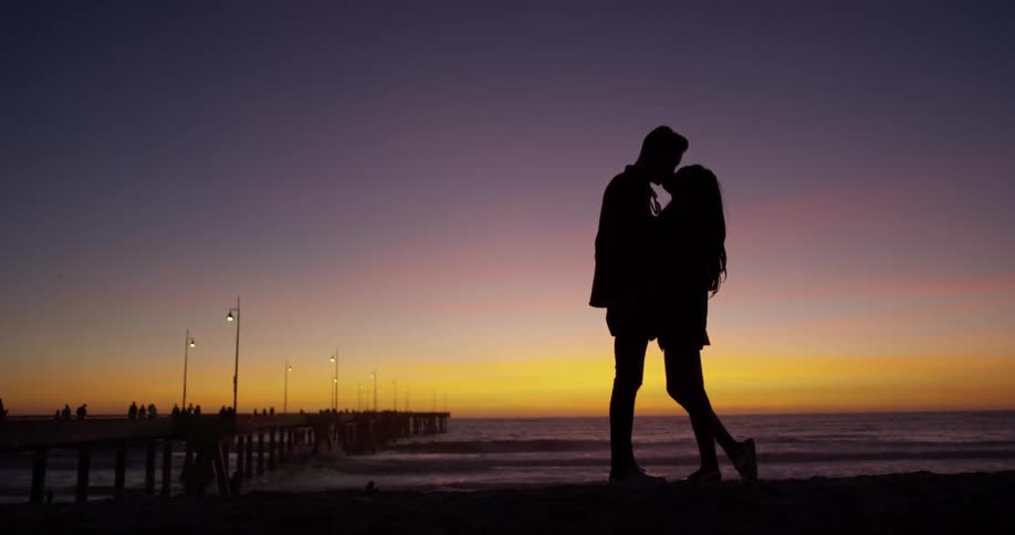 A man and woman kiss on the beach