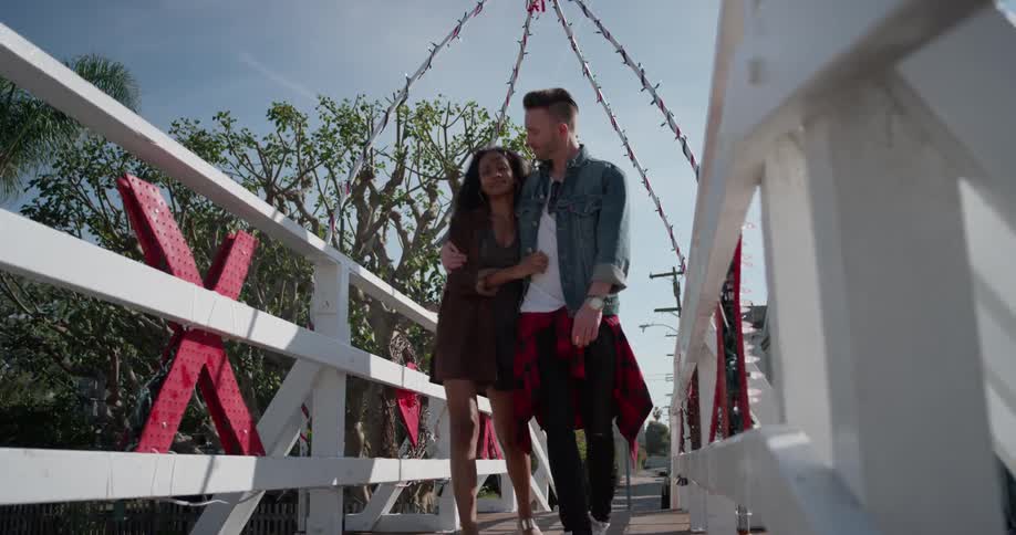 A man and woman hug as they walk over the bridge