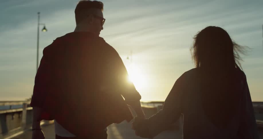 A man and woman hold hands as they walk