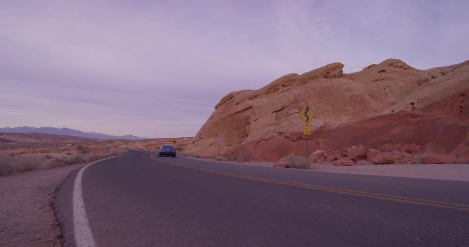 A car drives on the rural desert road
