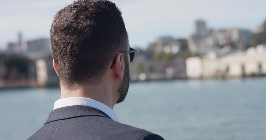 A man looks out onto the water by the city