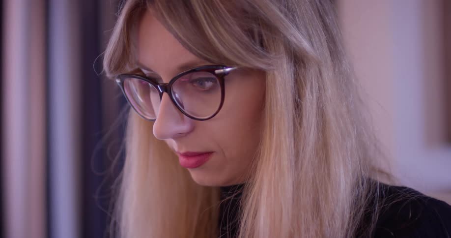 Woman wearing glasses stands in a room looking down