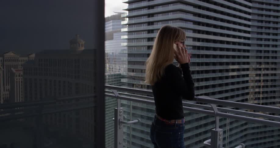 A woman uses a phone on the balcony