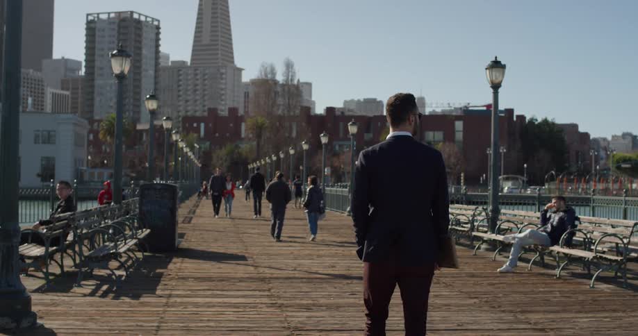 Man wearing sunglasses walks near the lake in the city