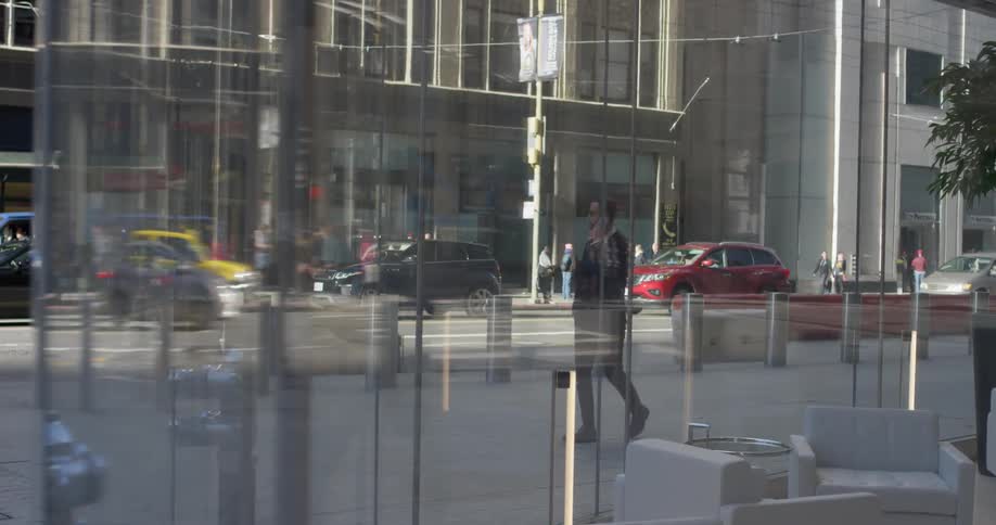 A man in a suit walks outside of a glass building
