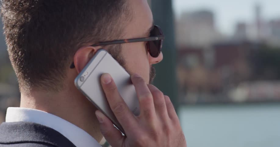 Man wearing sunglasses holds a cellphone to his ear
