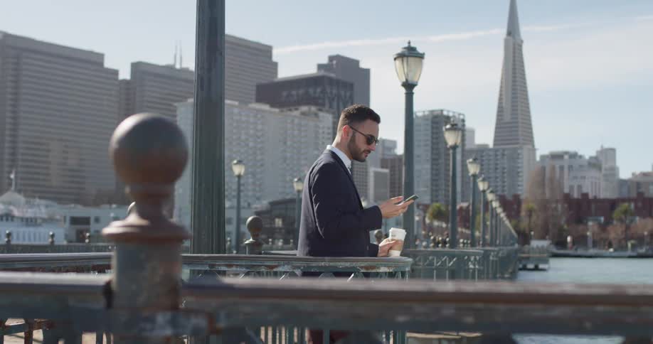Man wearing sunglasses holds a cellphone to his ear then lowers it