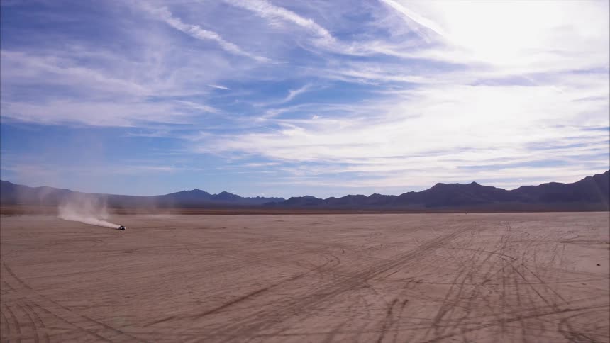 Vehicle travels over the sandy field under a blue sky
