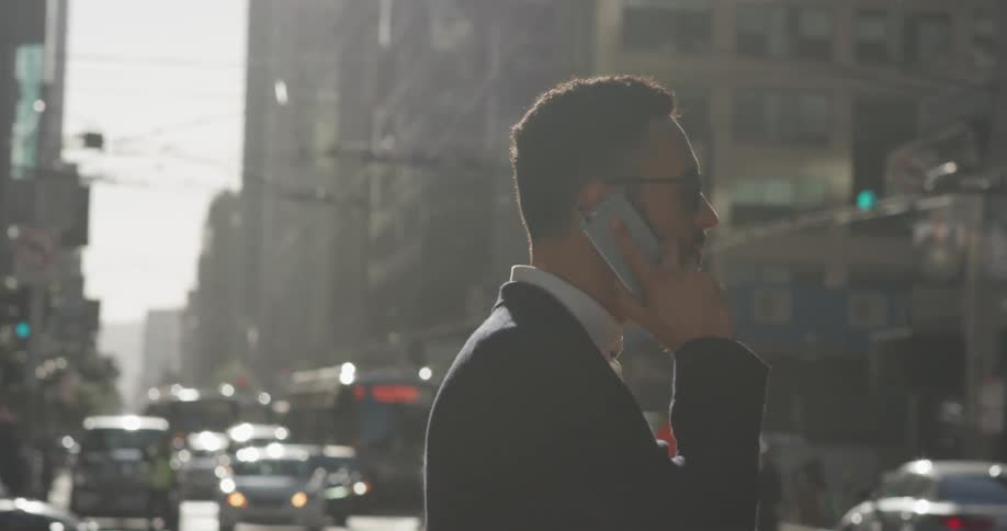 Man talks on a phone in the city on a sunny day