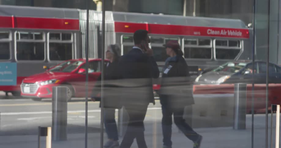 A man in a suit uses the phone as he walks