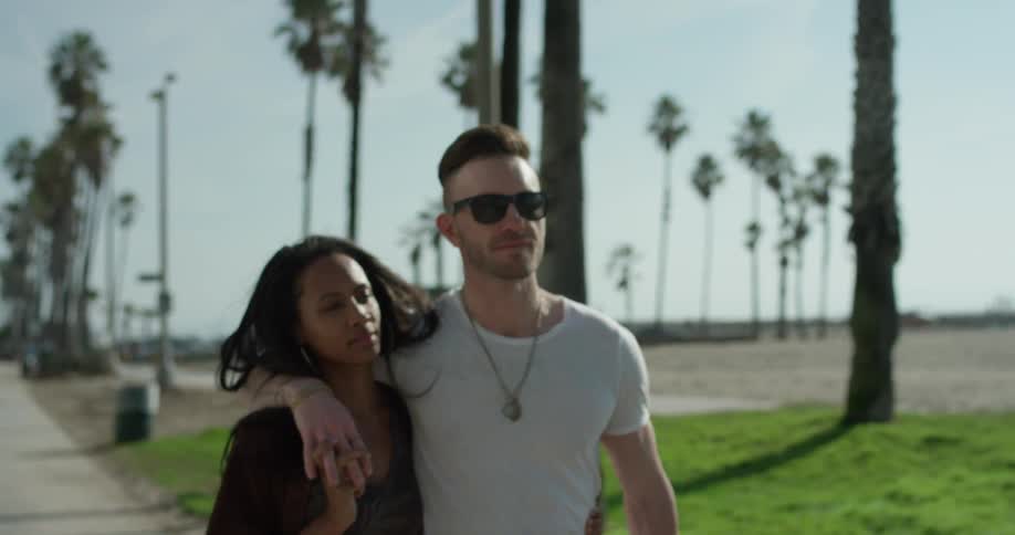 A man and woman walk together by the beach