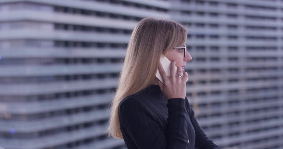 Woman standing outside during the day talking on the phone in the city