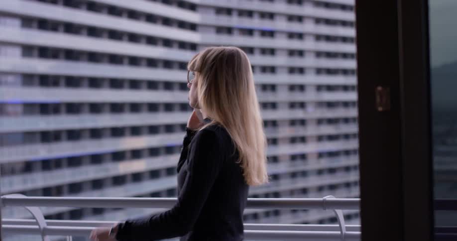 Woman talks on a cellphone as she walks on a balcony
