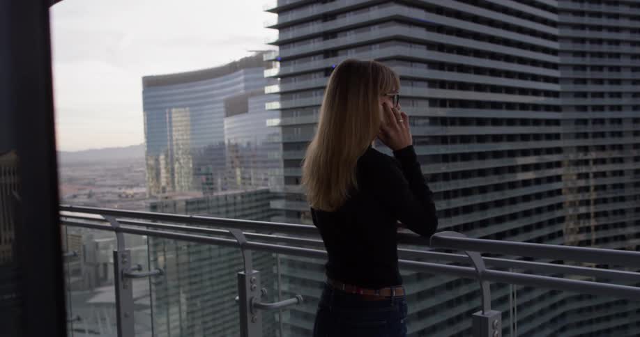 A woman uses a phone on the balcony