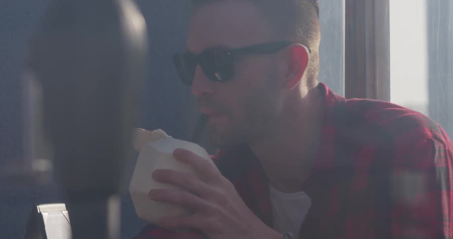Man is drinking from straw out of coconut