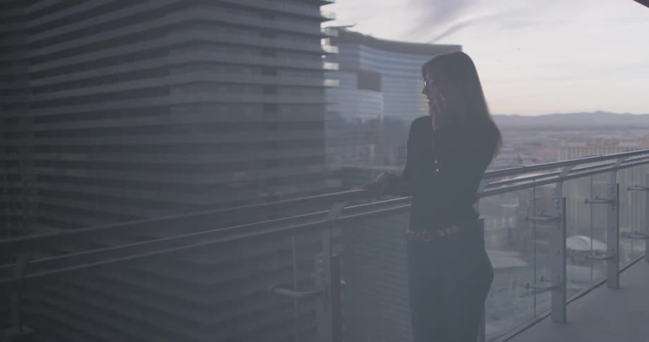 A woman uses her phone outside on the balcony