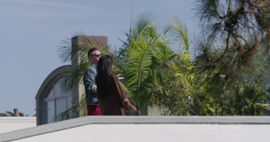 A man and woman hold hands and then hug on the bridge