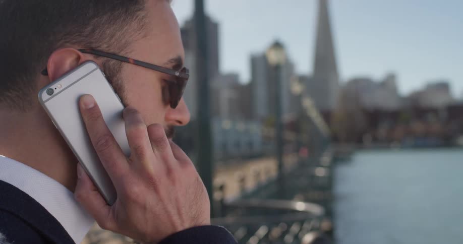 A man talks on a phone on a city pier