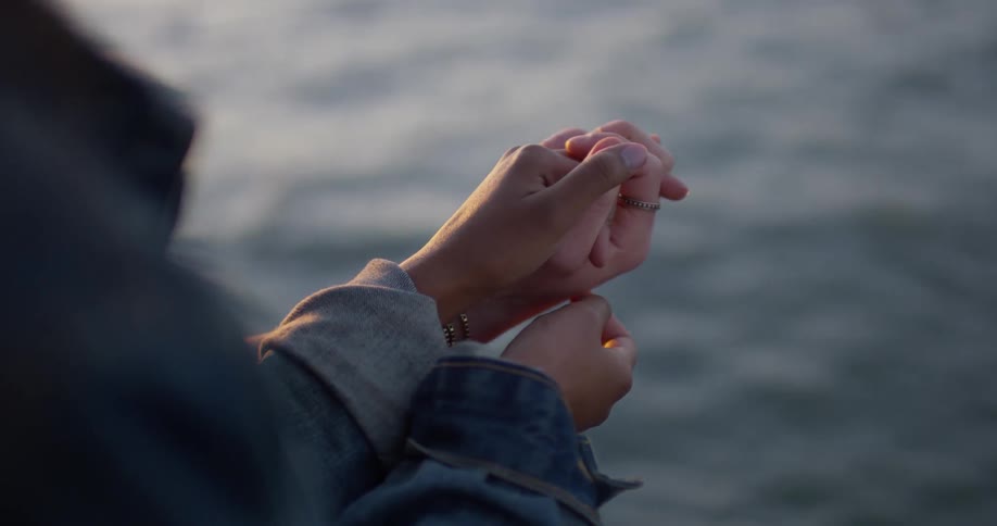 Couple is holding hands while standing on ocean pier