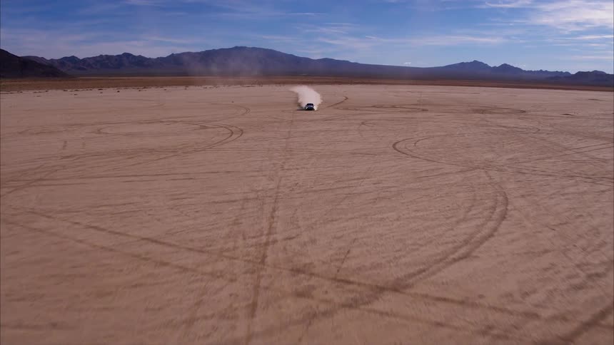 A car speeds across the desert