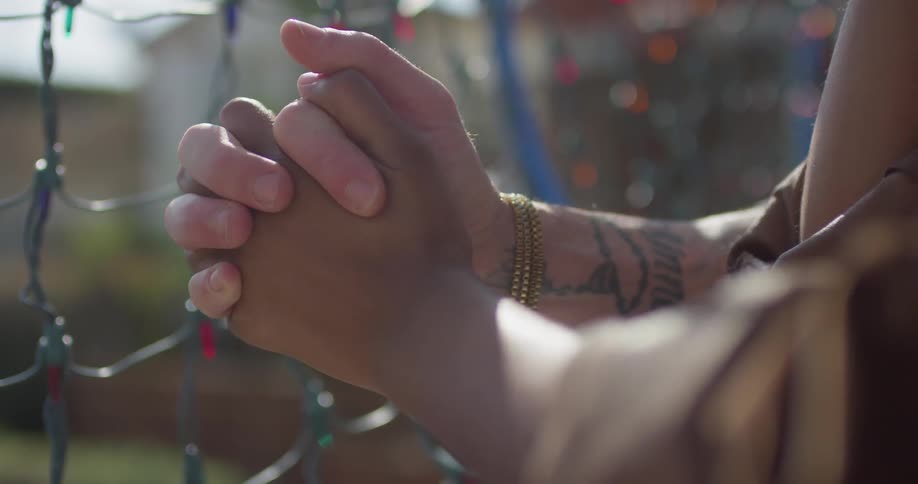 A man and woman hold hands by a fence