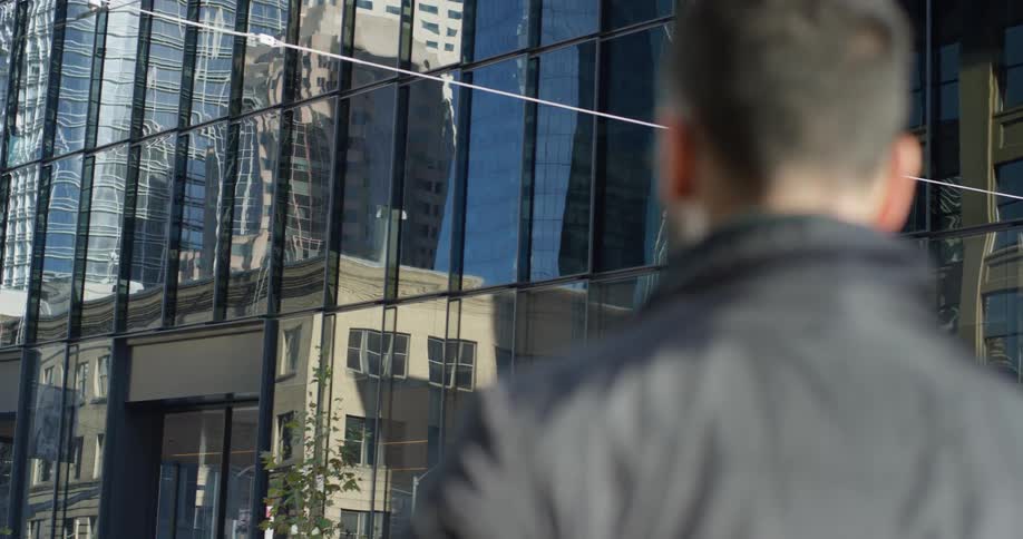 A man stands outside of a glass building