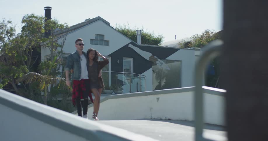 A man and woman embrace as they walk over the bridge