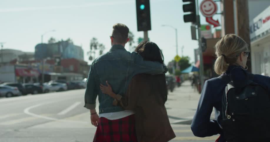 A couple are holding hands as they cross an intersection in daylight
