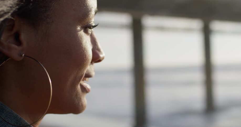 A woman smiles and laughs next to an ocean pier