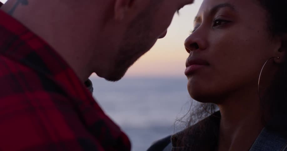 A man and woman embrace by the beach