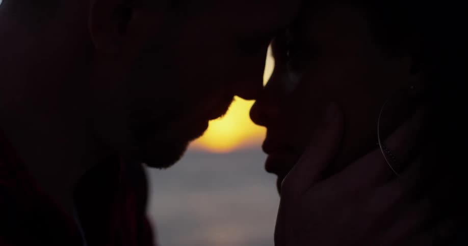 A man and woman embrace outside on the beach