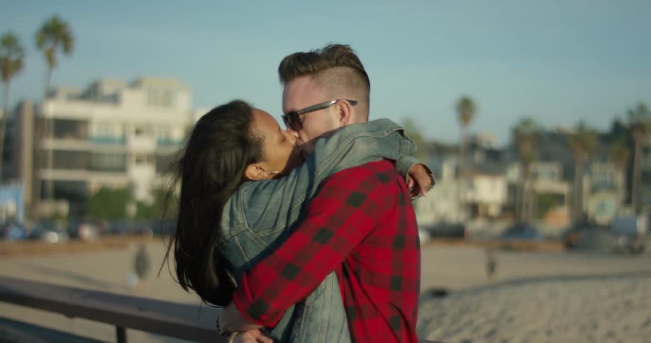 A man and woman kiss on the beach