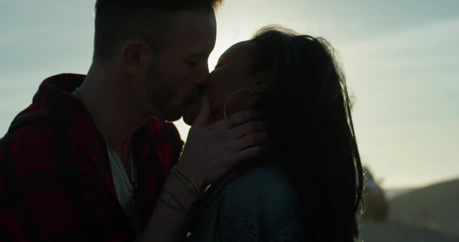 A man and woman kiss outside