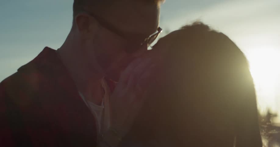 A man and woman embrace and kiss outside