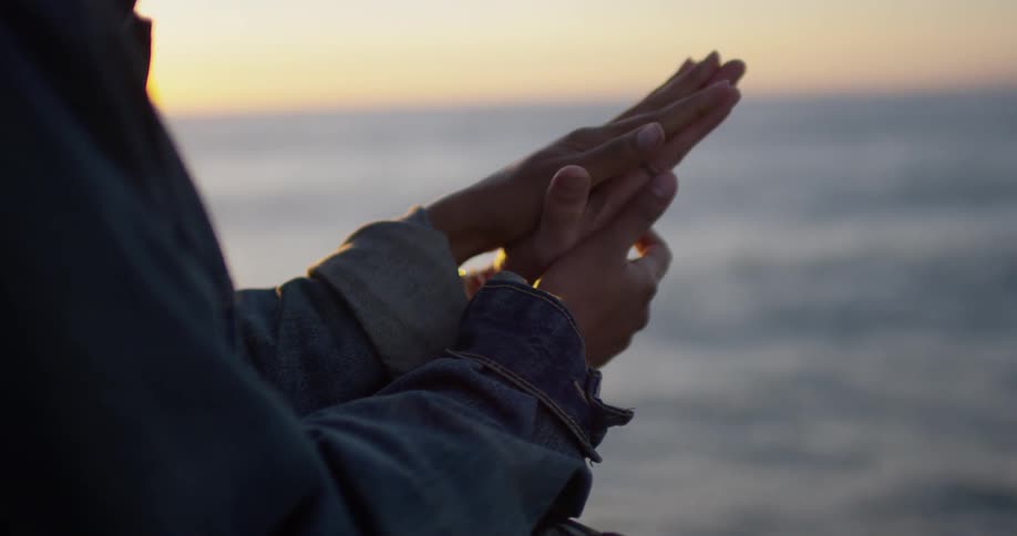 A man and woman hold hands on a beach at sunset