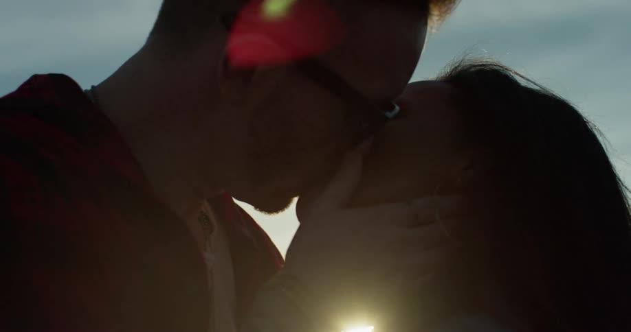 A man and woman kiss outside