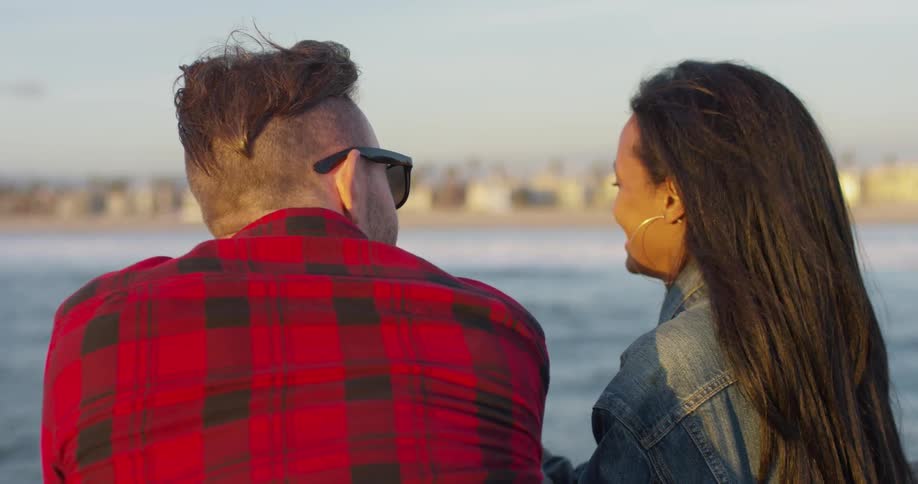 A man and woman stand together by the water
