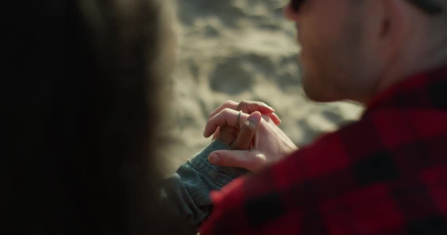 A man and woman hold hands on the beach