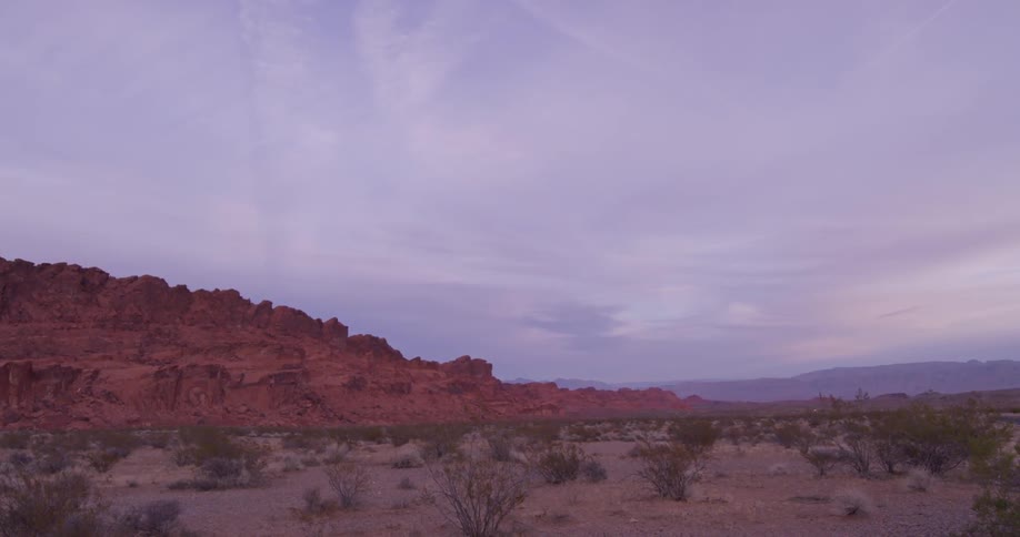 Clouds over brushy ground and rocky hills