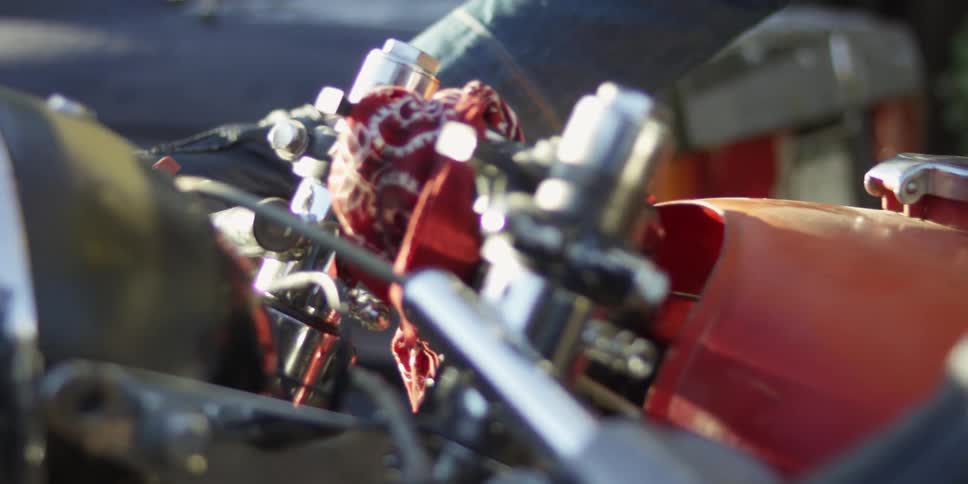 A man's hand resting on the handlebars of a motorcycle