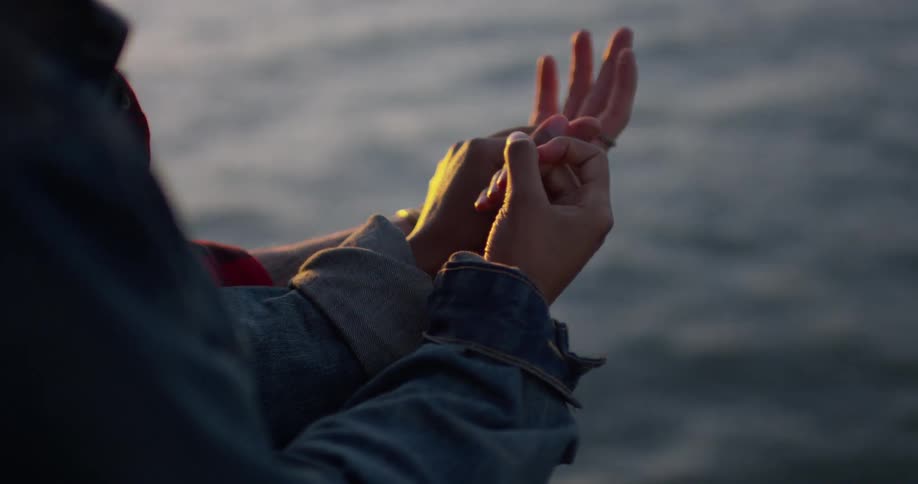 A man and woman hold hands by the water