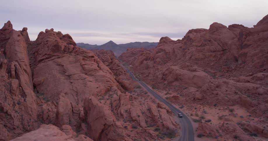Vehicle travels down the highway between the mountains under a cloudy sky