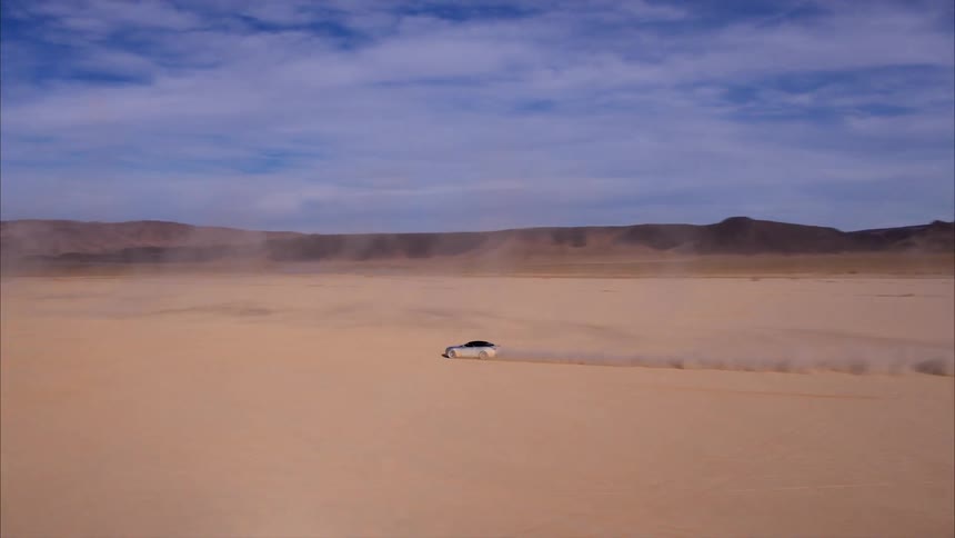 Car travels over the sandy land under a blue sky