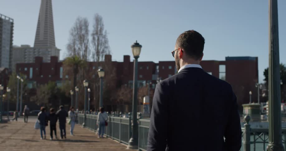 A man in a suit walks on the city pier