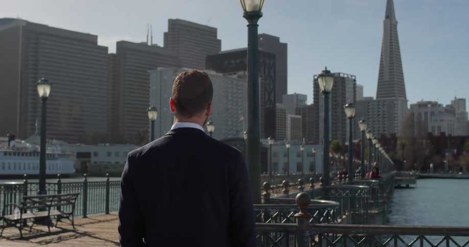 A man in a suit stands out on the city pier