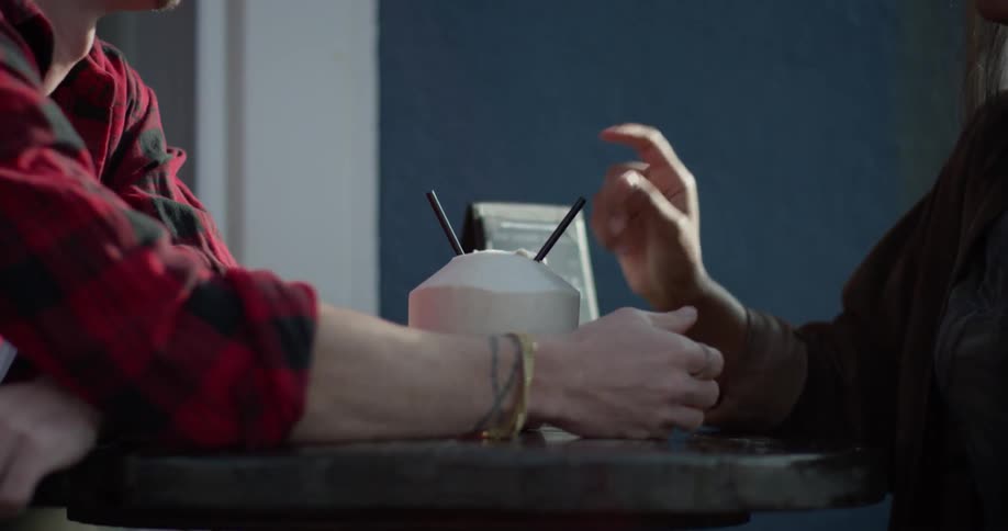 A couple share a drink and hold hands