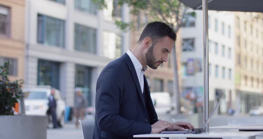 Man sitting outside working at a cafe in the city