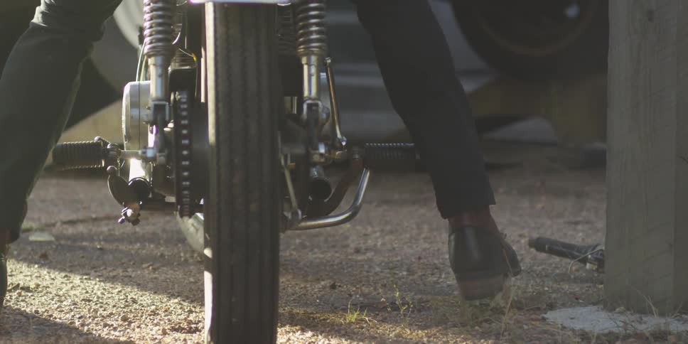 A man sits on a motorcycle and pushes with his feet